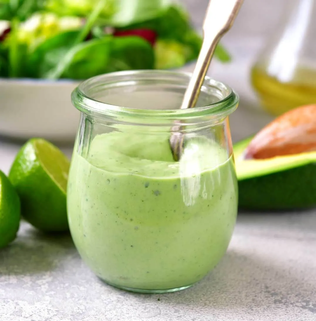 foto de una mezcla de mayonesa palta en un frasco de vidrio con el fondo de una mesa con verduras